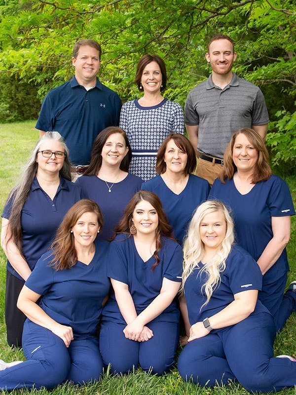 outdoor photo of the dentists and team at at Russellville Family Dentistry sitting on grass with trees behind them